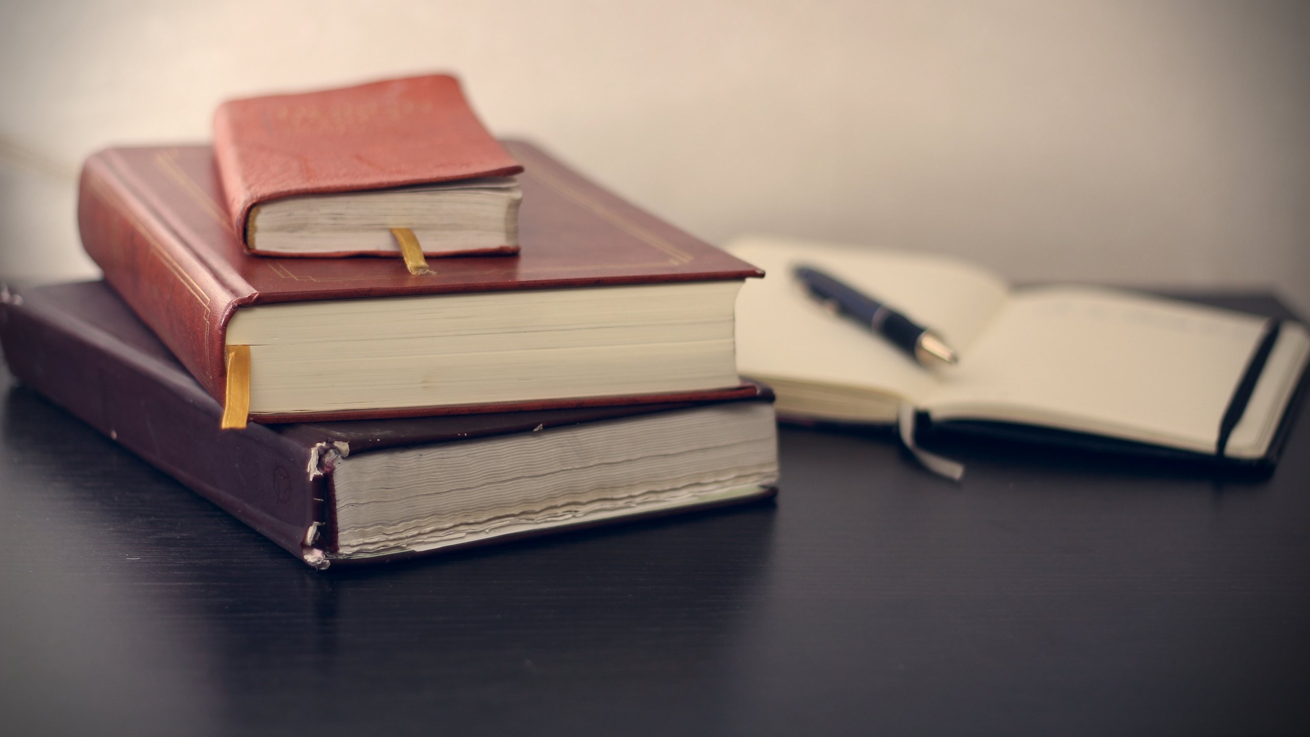 a stack of books and one open book and pen