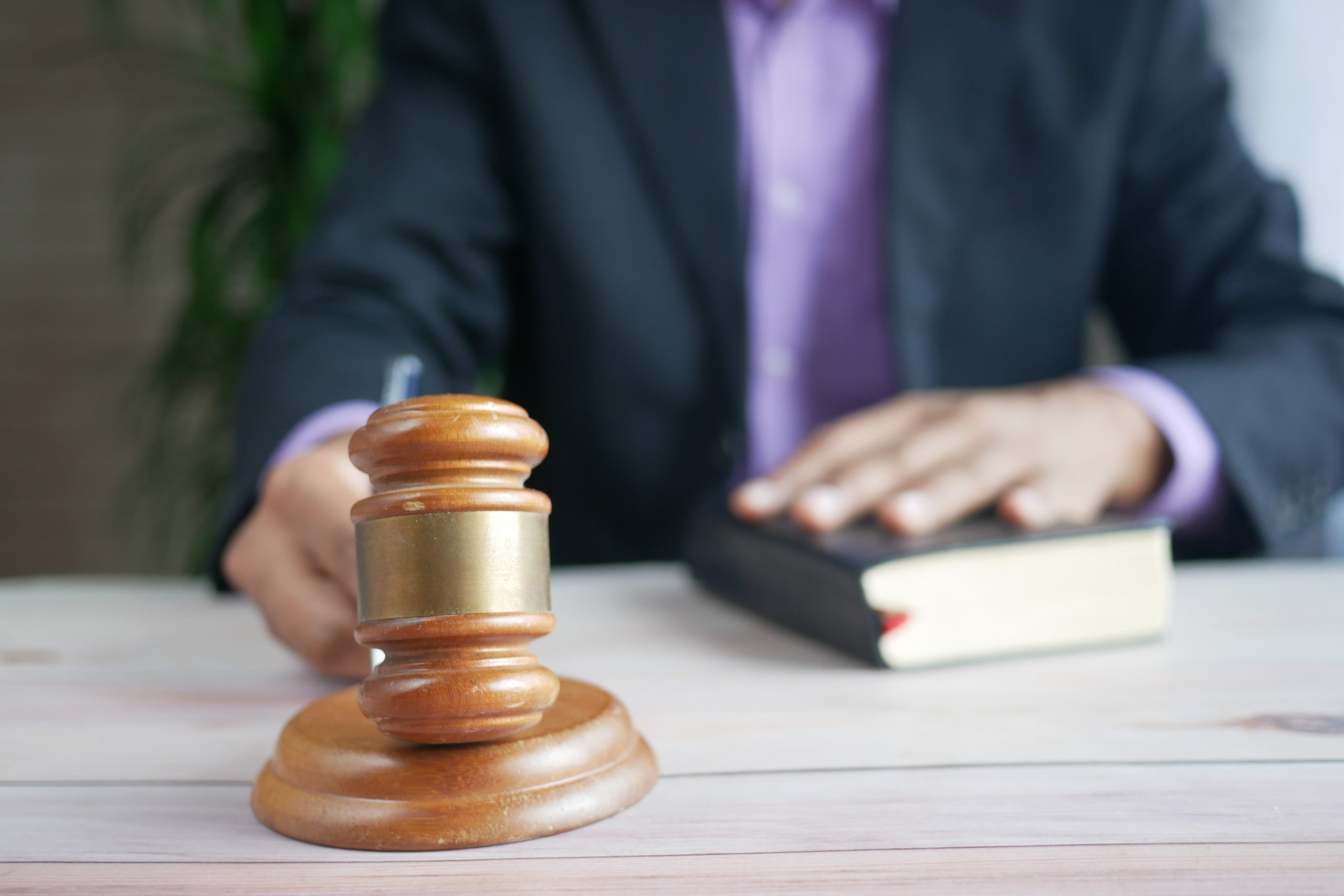 man holding judge's gavel and one hand on a book