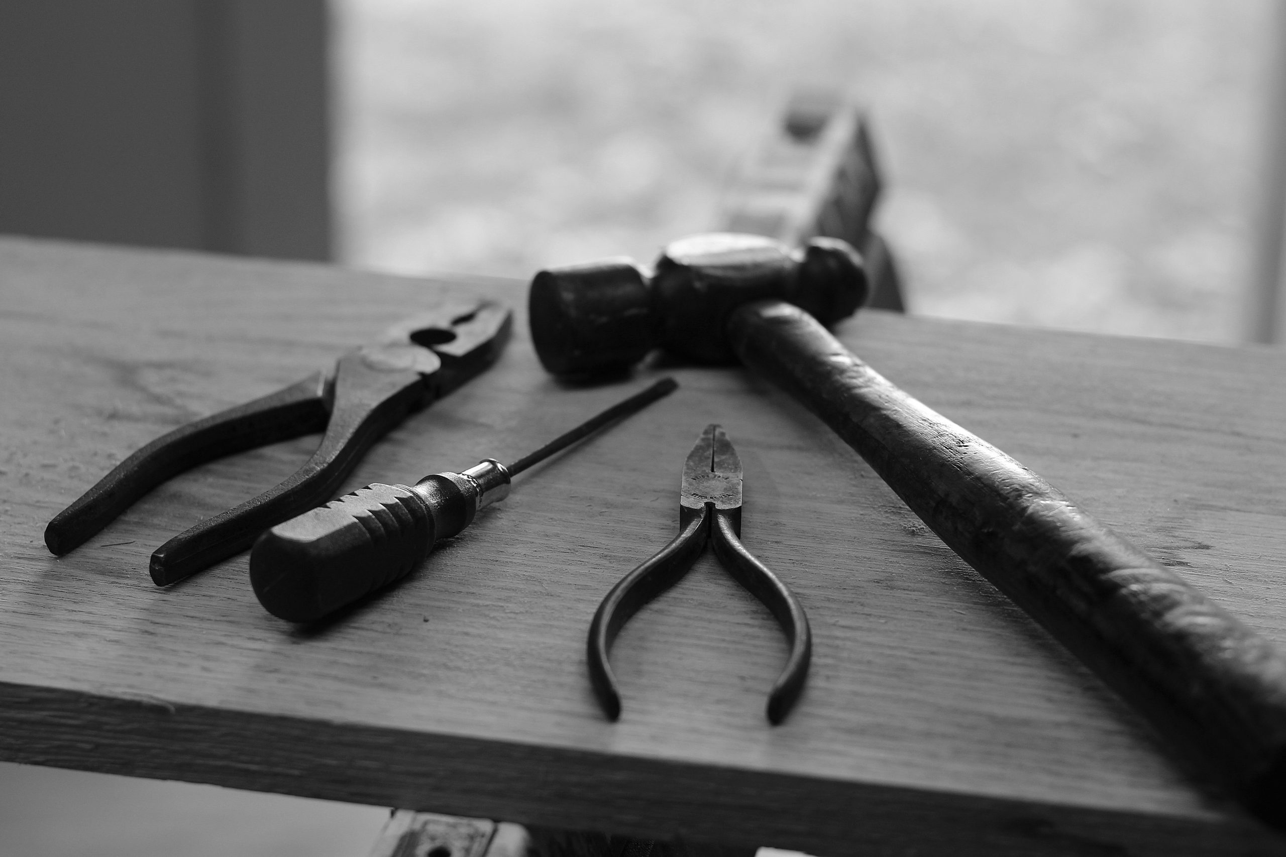 Black and white image of tools on a wooden workbench.