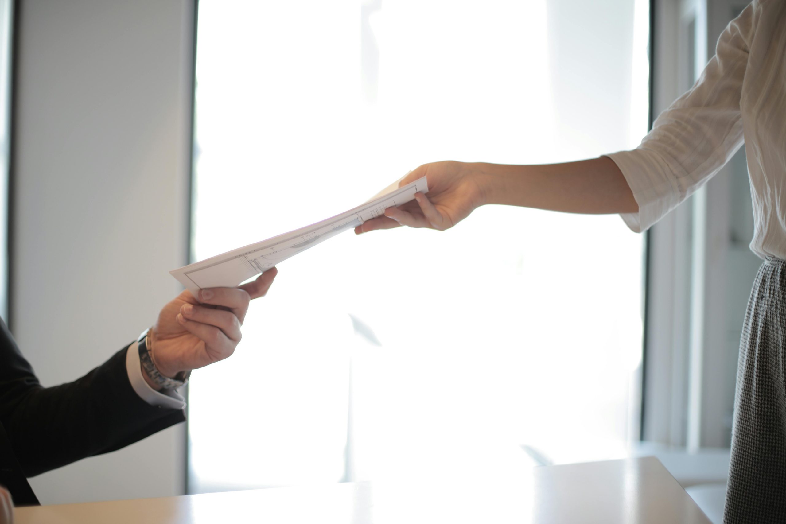 One person handing over an piece of paper to another person.