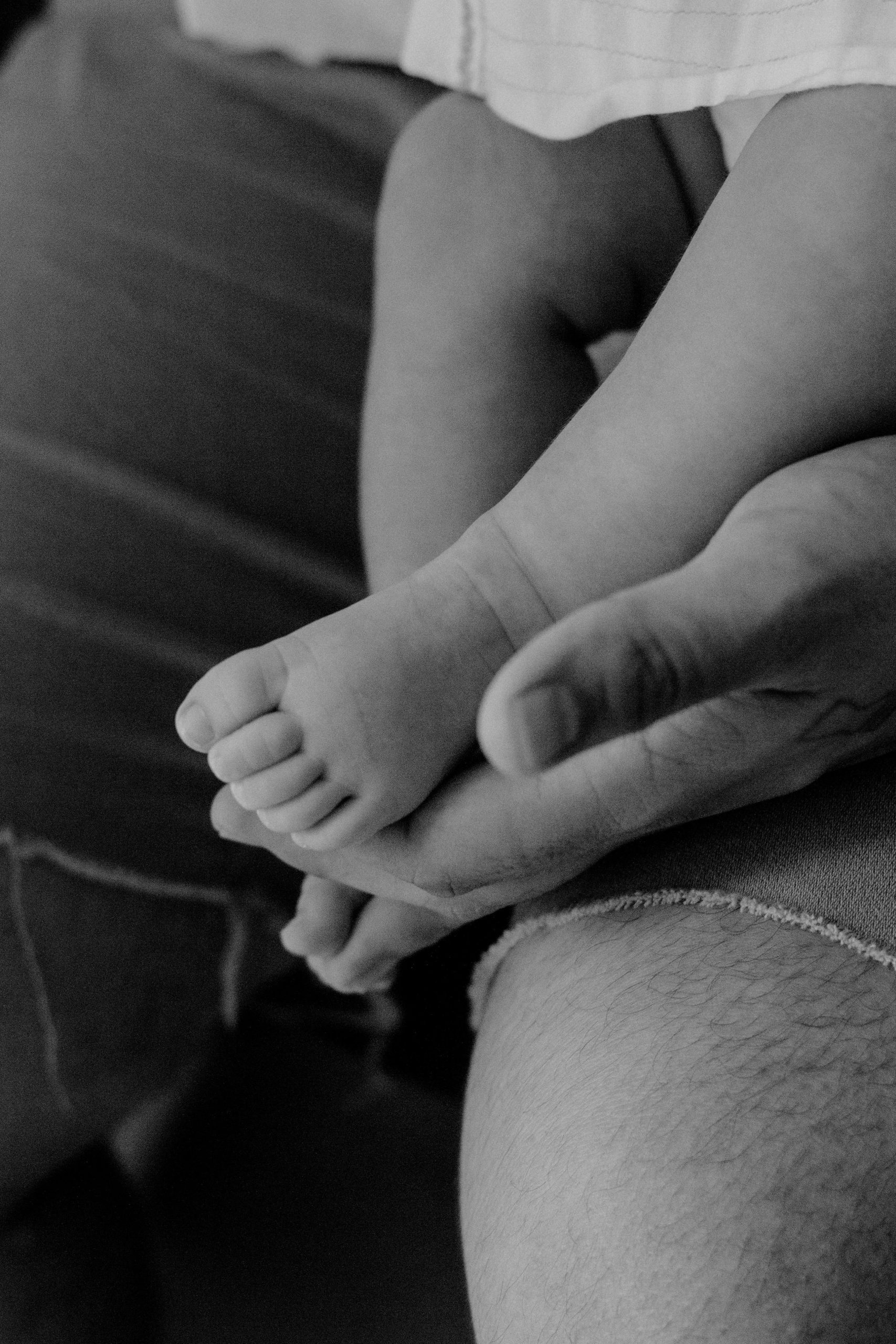 Close up of a man's hand holding a baby.