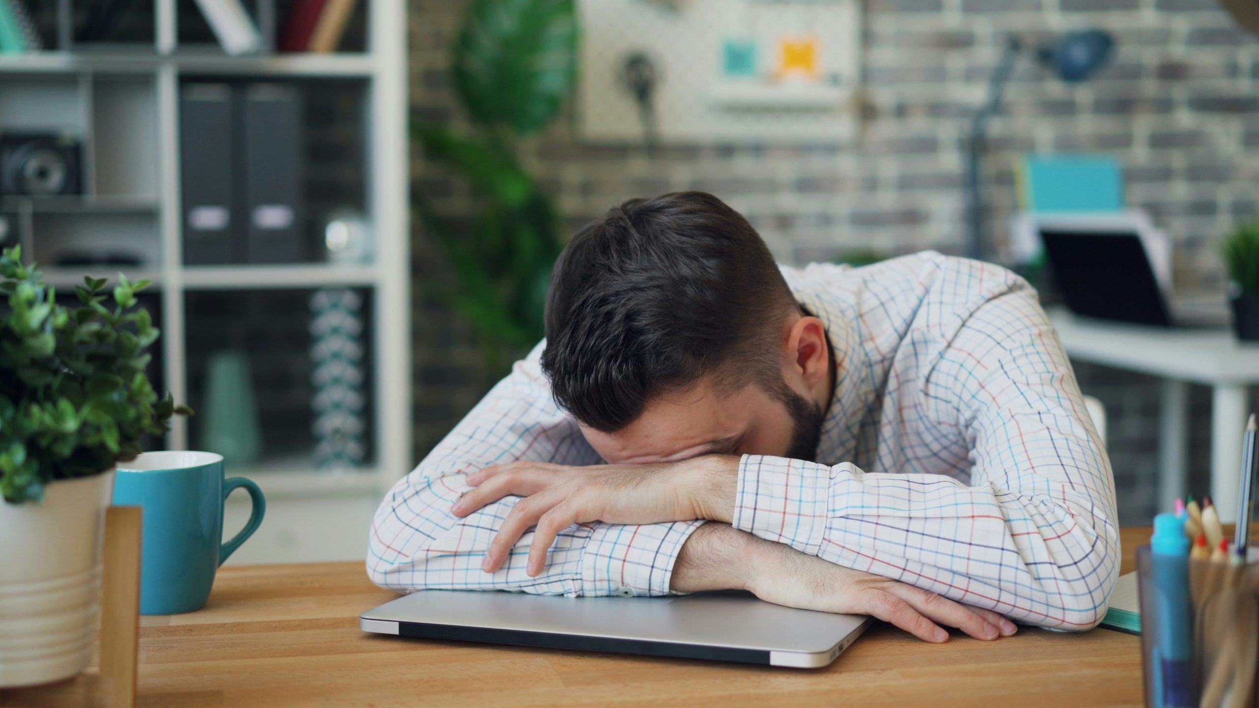 Man sitting at a table with his head in his hands.