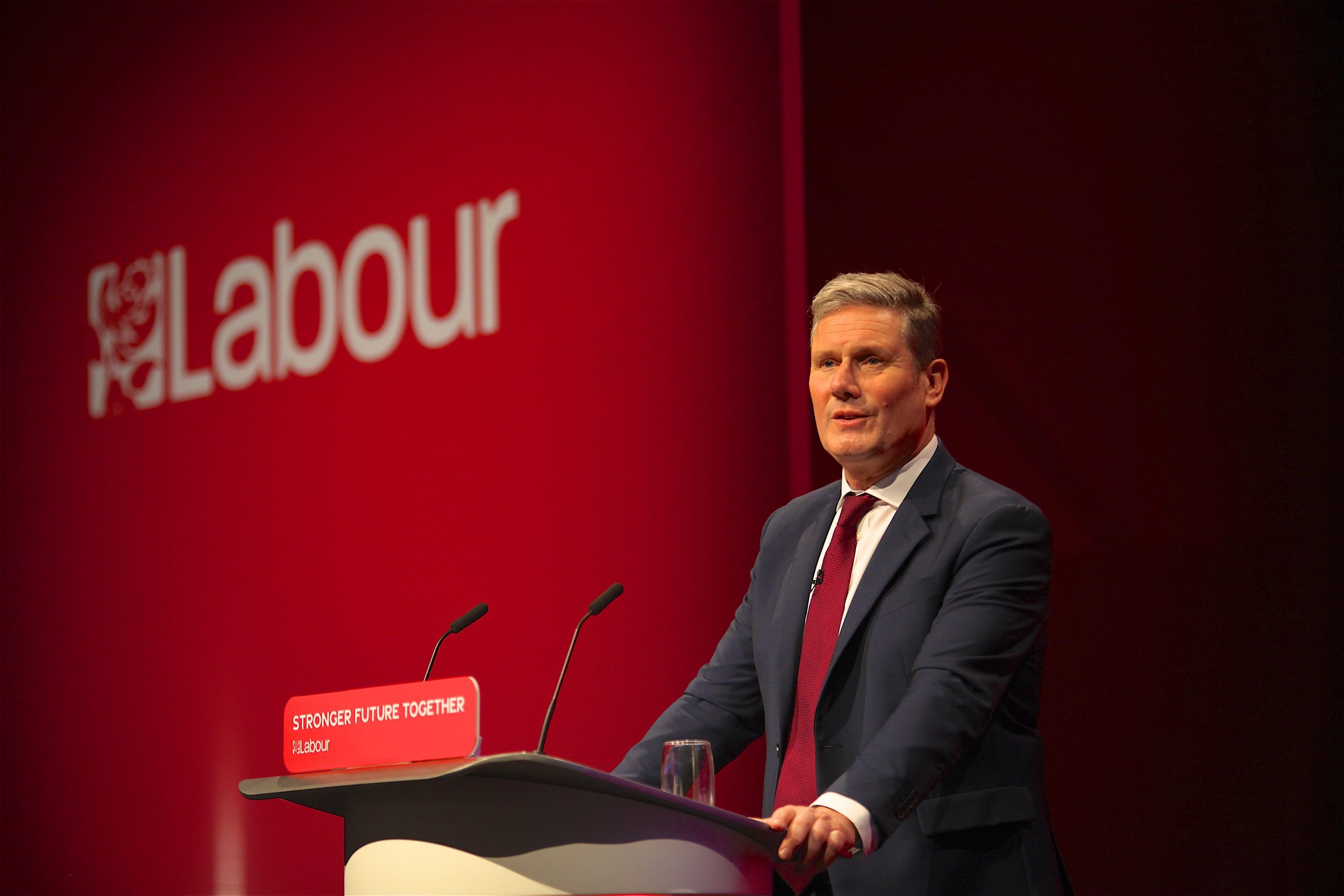 Kier Starmer giving a speech at a podium in front of a labour Party banner.